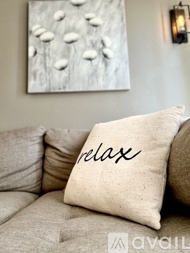 A cushion with the word "relax" on it is placed on a couch.