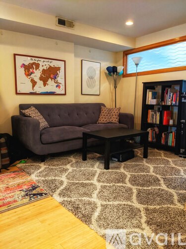 A living room with a grey couch and a world map on the wall.