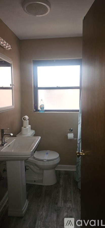 A bathroom with a toilet, sink, and window.