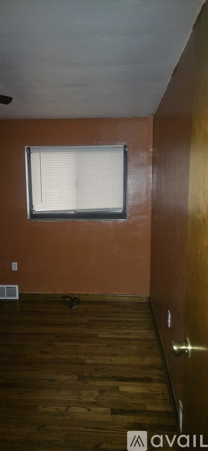 A room with wooden floors and a window with blinds.