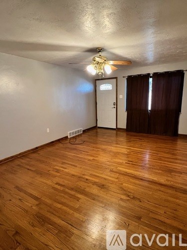 A room with wooden flooring and a ceiling fan.