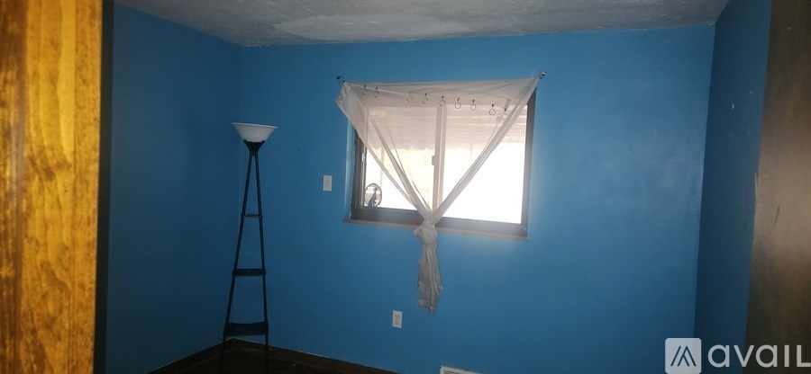 A room with blue walls and a window with a white curtain.