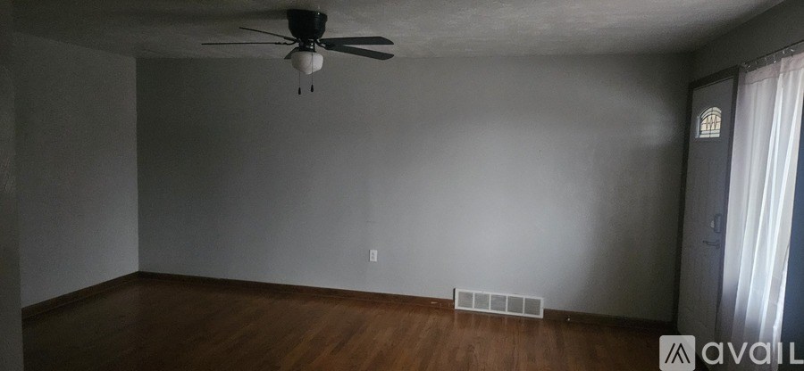 A room with a ceiling fan and wooden floors.