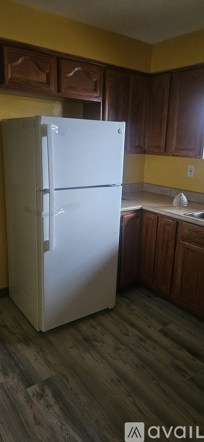 A white refrigerator in a kitchen with wooden cabinets.