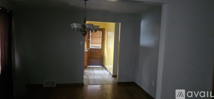 A hallway with a chandelier and a door at the end.