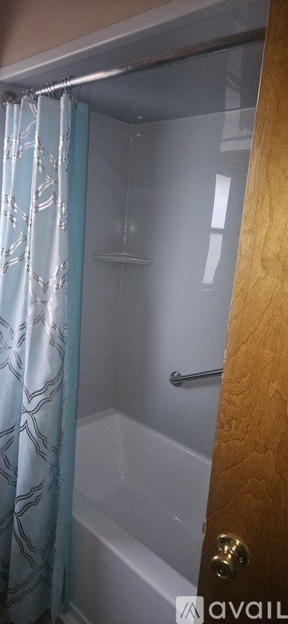 A bathroom with a shower and a blue curtain.