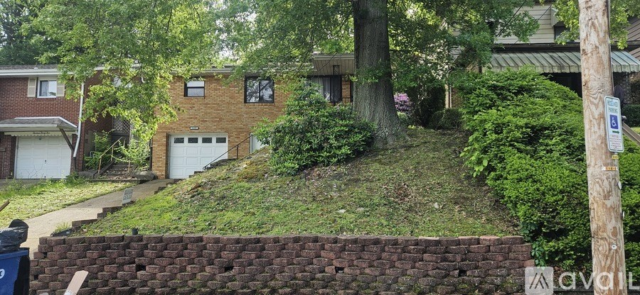 A house with a garage is surrounded by a brick wall and greenery.