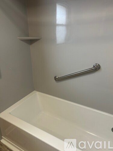 A white bathtub with a silver grab bar mounted on the wall.