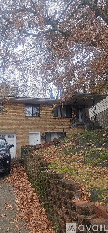 A house with a brick wall and a tree with brown leaves.