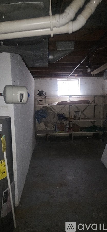 A room with a window and a white pipe on the wall.