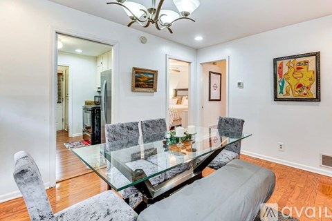 A modern dining room with a glass table and grey chairs.