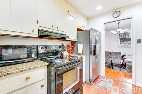 A kitchen with white cabinets and a stainless steel refrigerator.