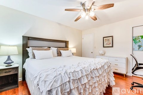 A bedroom with a large bed and a ceiling fan.