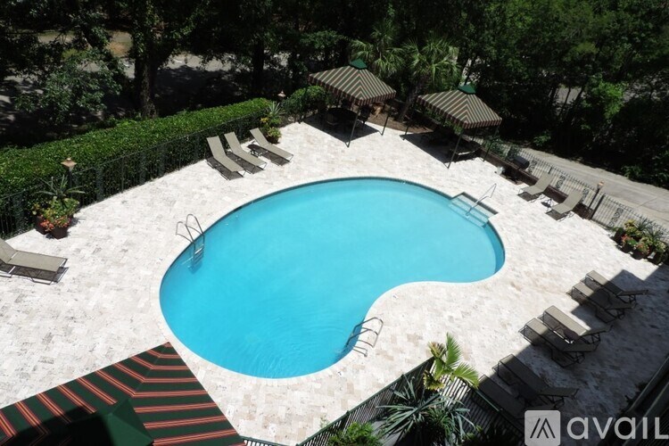 A pool surrounded by trees and lounge chairs.