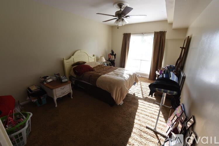 A bedroom with a bed, chair, and a fan.