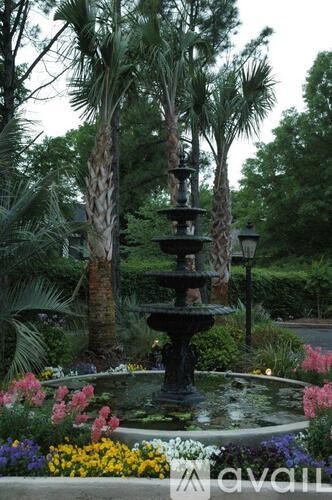 A fountain in the middle of a garden surrounded by flowers.