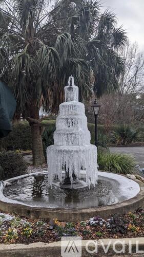 A frozen fountain in a park surrounded by trees.