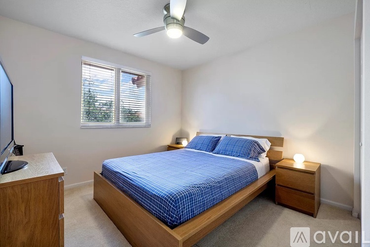 A bedroom with a bed, nightstand, and window with blinds.