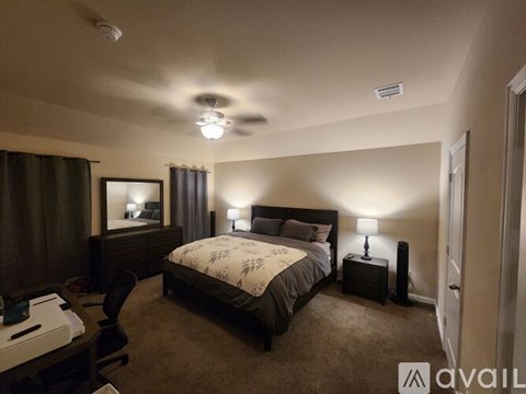 A bedroom with a large bed and a ceiling fan.