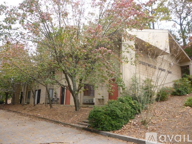 A building with the words "Sweetwater Springs" on the side is surrounded by trees and bushes.