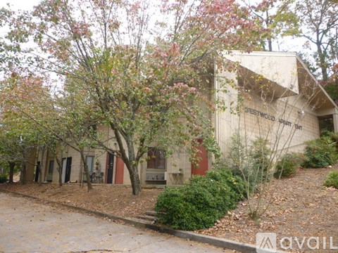 A building with the words "Sweetwater Springs" on the side is surrounded by trees and bushes.