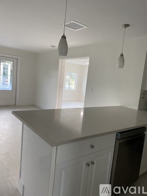 A kitchen with a large island and pendant lights.