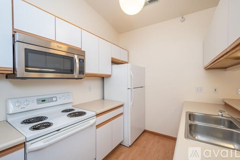A kitchen with white appliances and wooden cabinets.