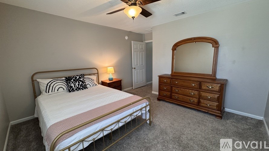 A bedroom with a bed, dresser, and mirror.
