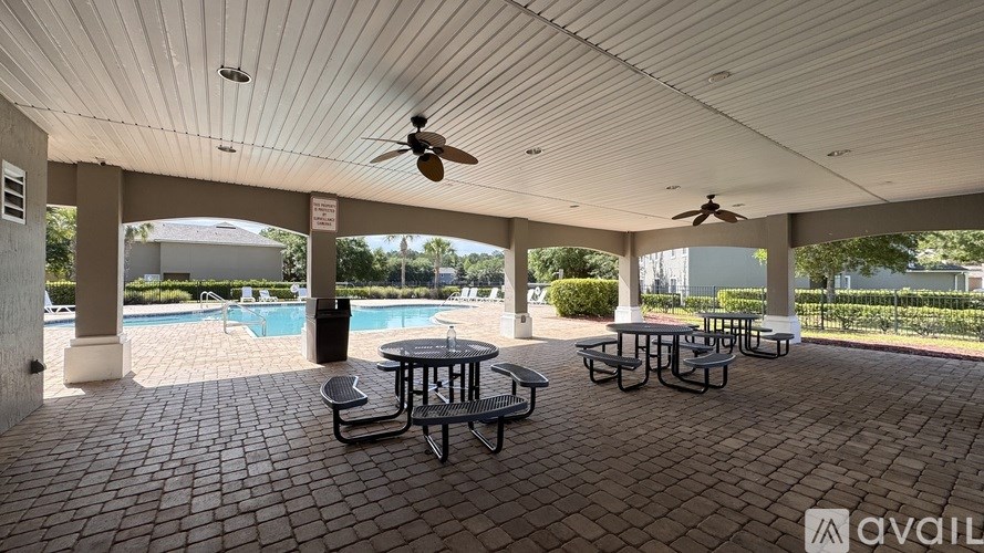 A patio with a table and chairs and a pool in the background.