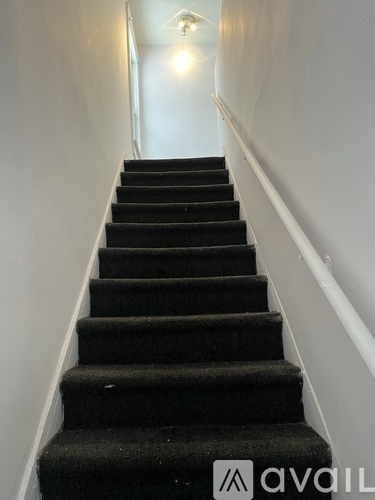 A staircase with a carpeted runner and white walls.