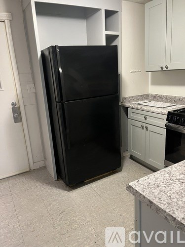 A black refrigerator in a kitchen with granite countertops.