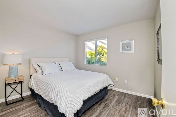 A bedroom with a large bed and a window with blinds.