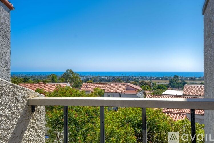 A balcony overlooks a residential area with houses and trees.