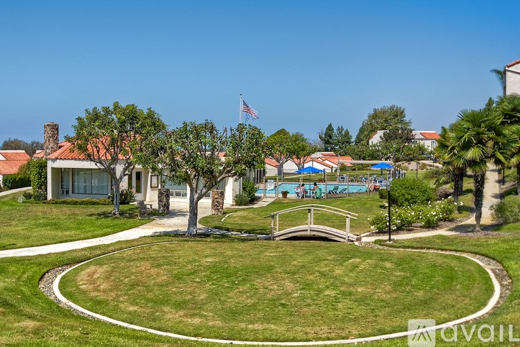 A park with a bridge and a pool in the background.