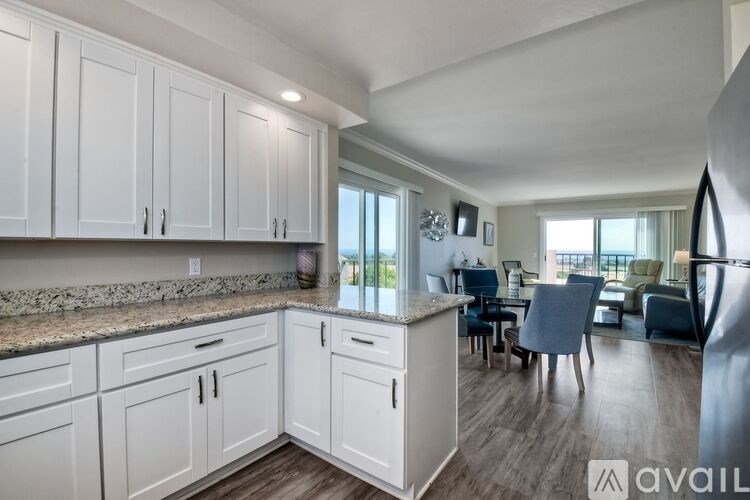 A kitchen with white cabinets and a marble countertop.