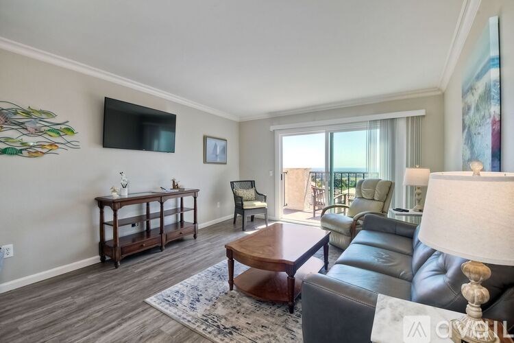 A living room with a grey couch, a wooden coffee table, and a flat screen TV mounted on the wall.