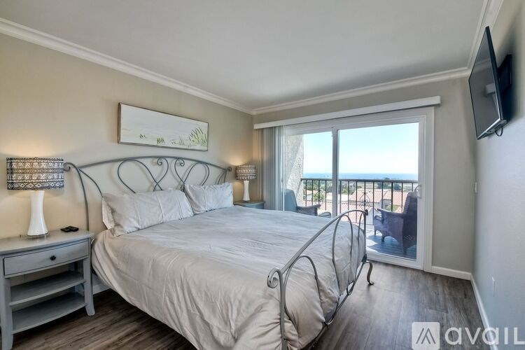 A bedroom with a large bed and a balcony overlooking the ocean.