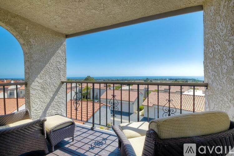 A balcony with two chairs and a table overlooking the sea.