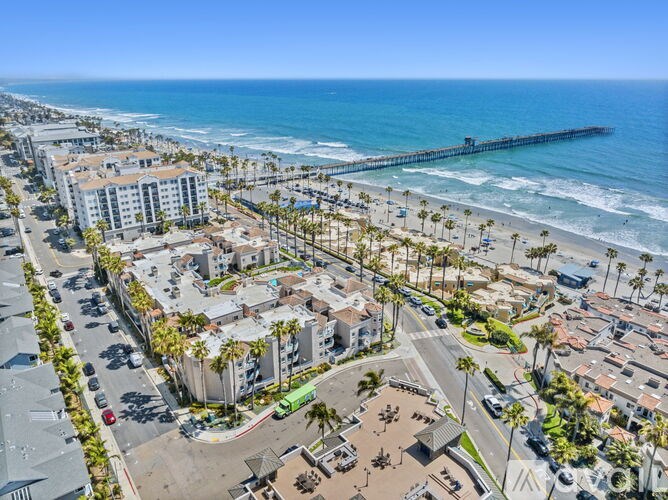 A beachfront area with a pier in the distance.