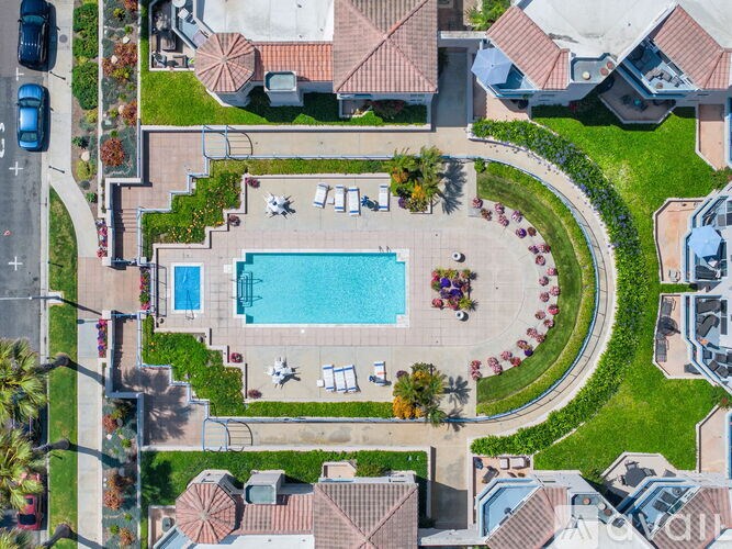 A swimming pool surrounded by a grassy area and a few chairs.