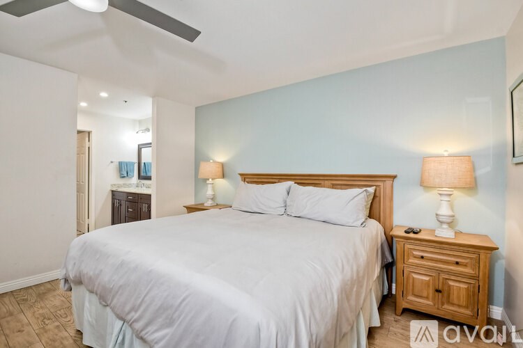 A bedroom with a large bed, two lamps, and a wooden nightstand.