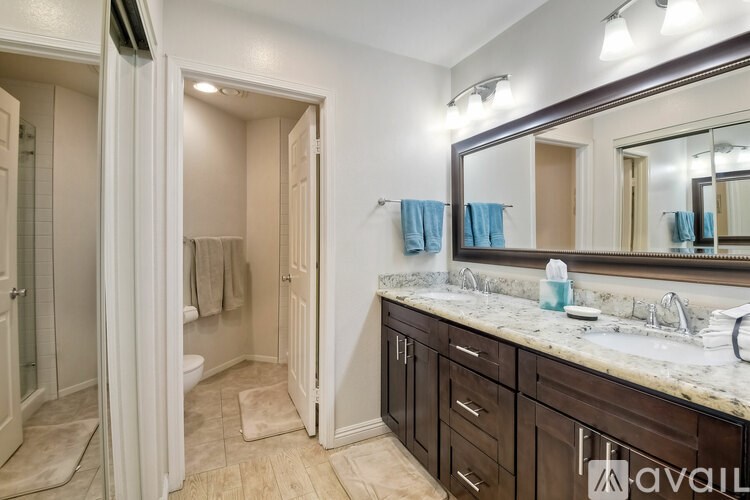 A bathroom with a sink, mirror, and a towel hanging on the door.