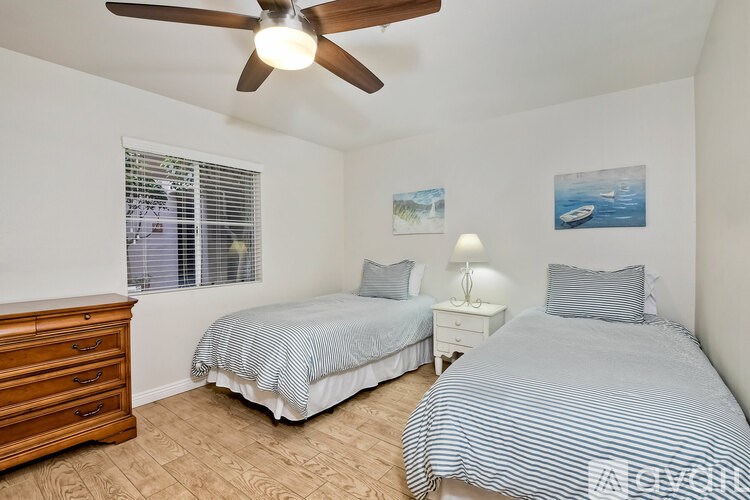 A bedroom with two beds and a ceiling fan.