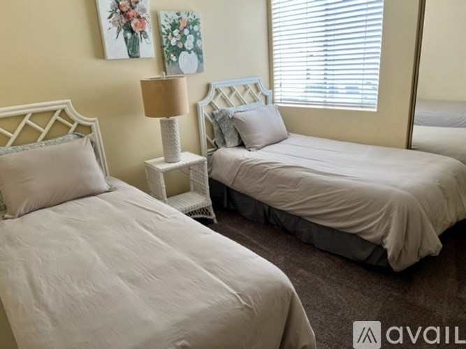 Two beds with pillows and a lamp in a room.