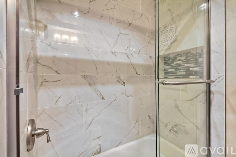 A bathroom with a marble tile wall and a glass shower door.