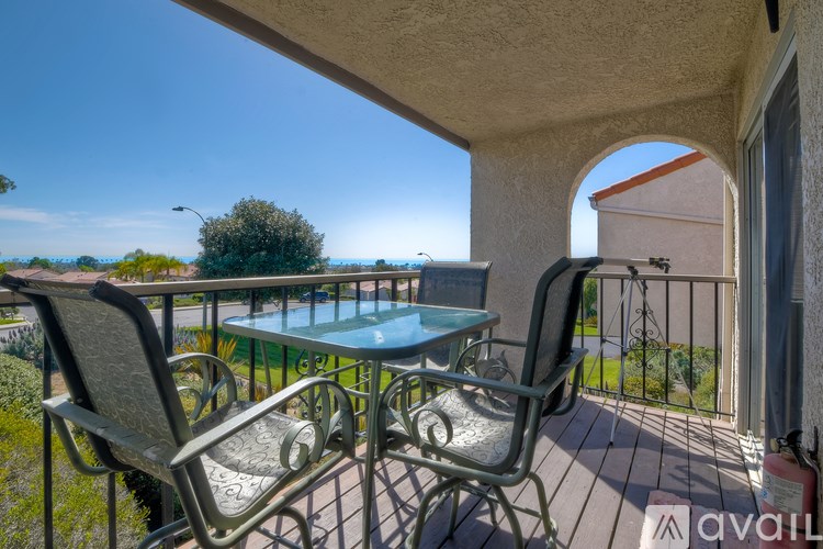 A balcony with a table and two chairs overlooking a garden.