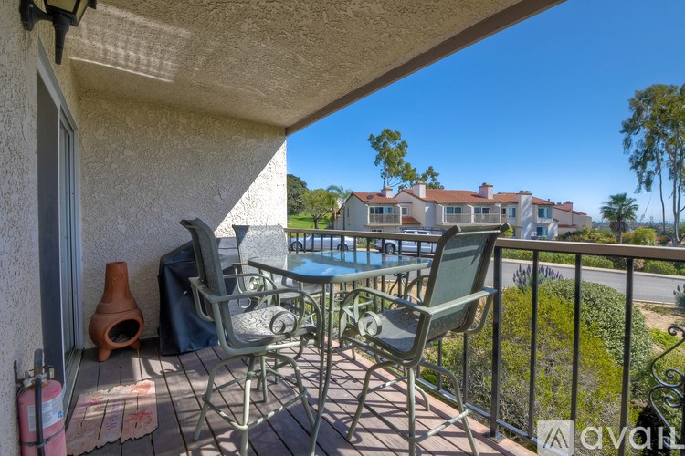 A patio with chairs and a table is overlooking a pool and a building.