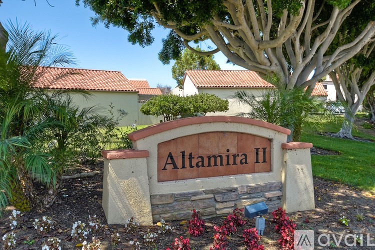A sign that says "Altamira II" is in front of a tree.