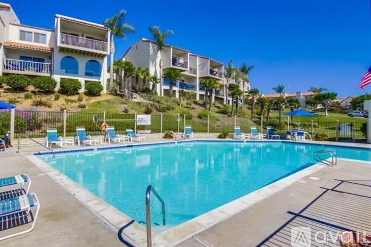A pool with a fence and chairs around it.