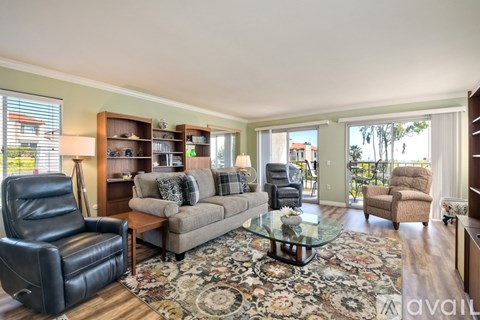 A living room with a black leather chair and a glass coffee table.